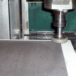 Working on a porous CFK-workpiece with a perforated grid-hole chuck incl. a fleece foil which allows to cut through.